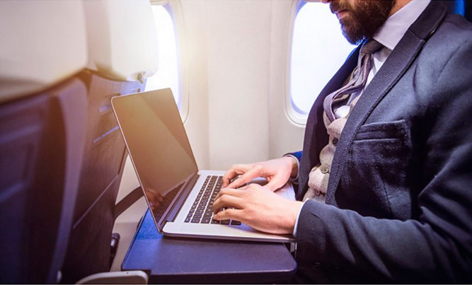 Man typing on laptop on a plane